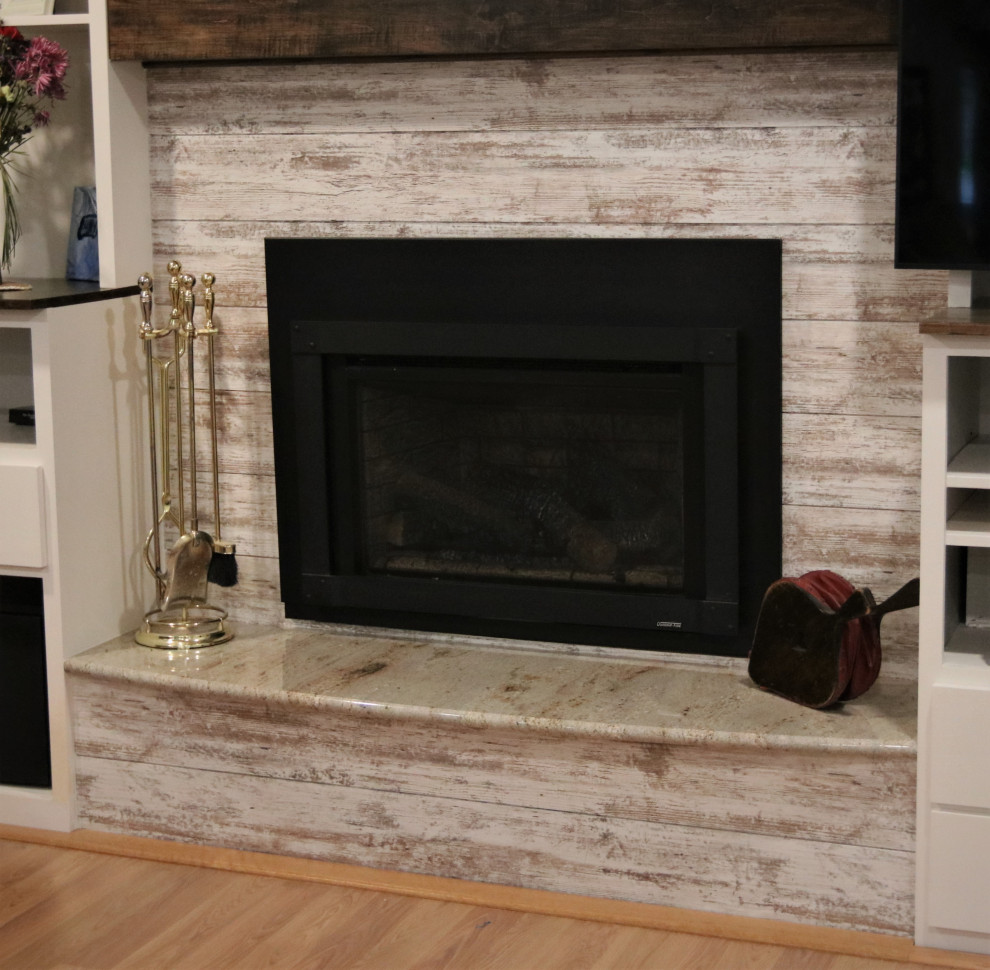 他の地域にある低価格の中くらいなラスティックスタイルのおしゃれなLDK (白い壁、淡色無垢フローリング、標準型暖炉、塗装板張りの暖炉まわり、据え置き型テレビ、マルチカラーの床) の写真