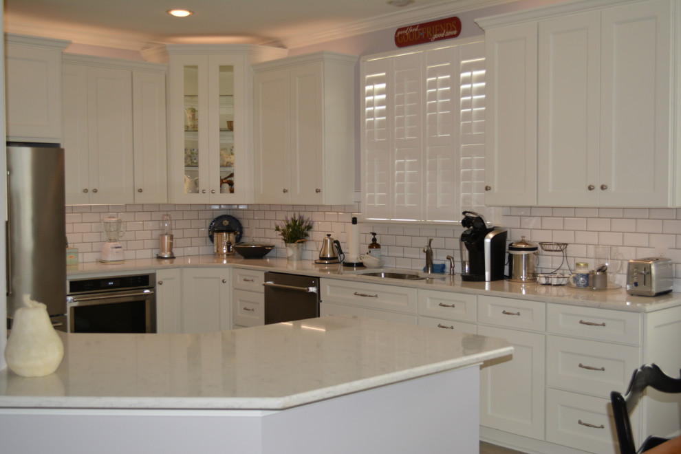 This is an example of a medium sized traditional u-shaped kitchen/diner in Other with a submerged sink, flat-panel cabinets, white cabinets, engineered stone countertops, yellow splashback, ceramic splashback, stainless steel appliances, porcelain flooring, an island, brown floors and grey worktops.