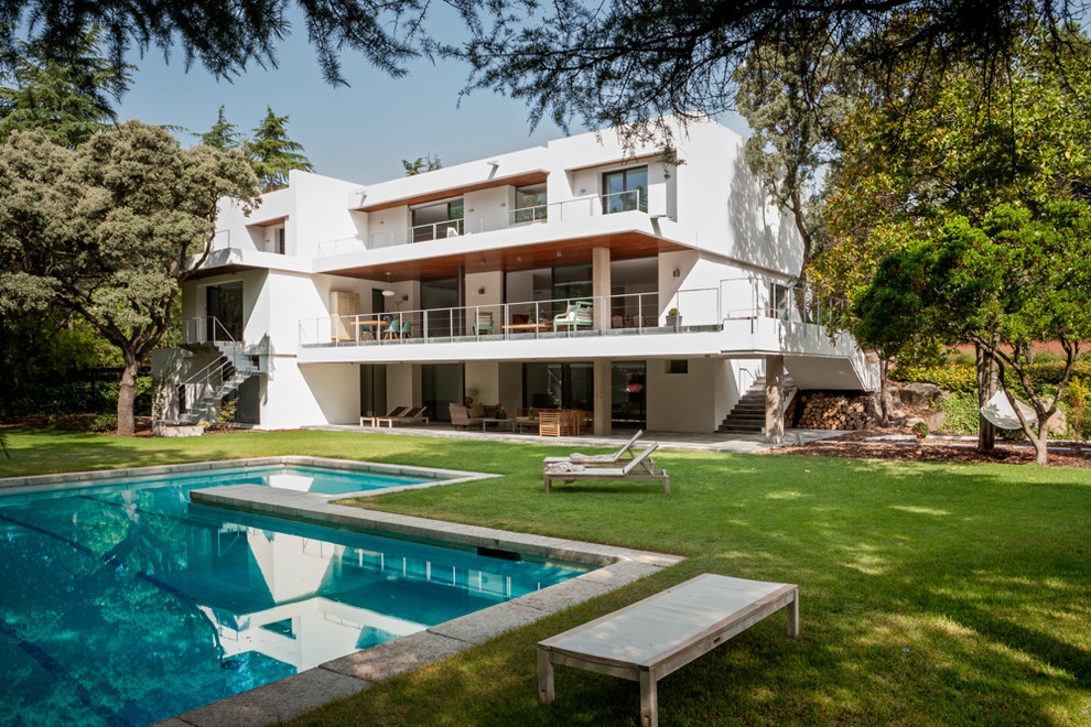 Ejemplo de fachada blanca contemporánea grande de tres plantas con revestimiento de estuco y tejado plano