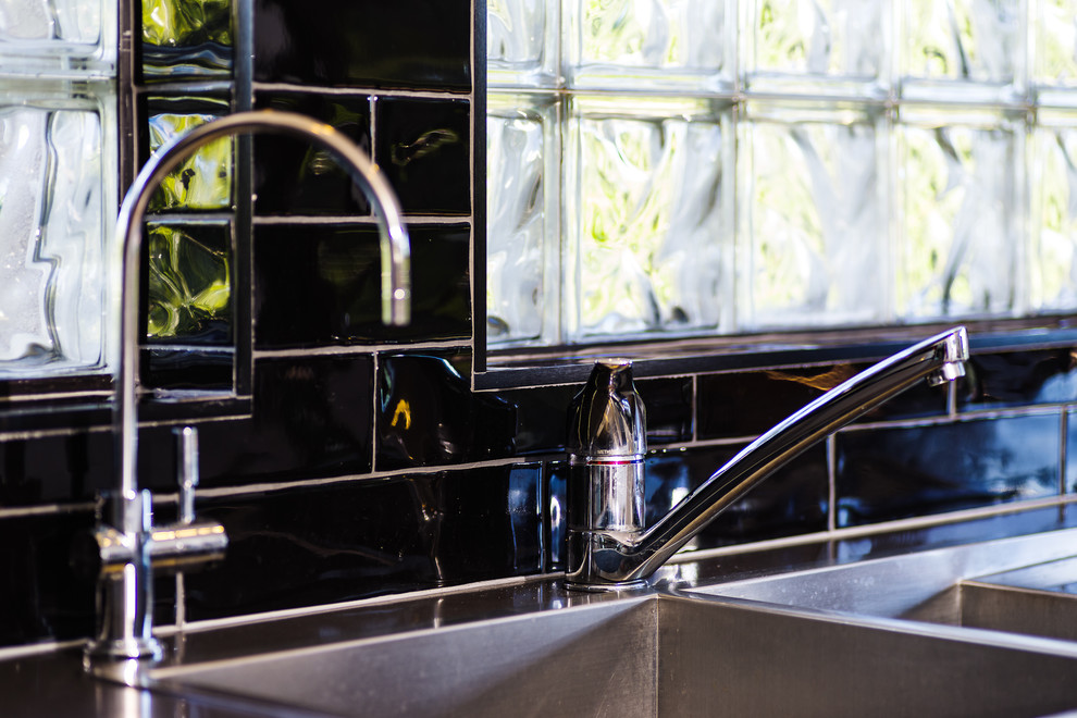 Design ideas for a modern l-shaped eat-in kitchen in Gold Coast - Tweed with a double-bowl sink, flat-panel cabinets, white cabinets, quartz benchtops, black splashback, subway tile splashback, stainless steel appliances, medium hardwood floors, with island and brown floor.
