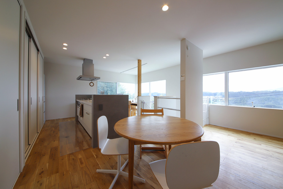 Modern open plan dining in Other with white walls, medium hardwood floors, brown floor and wallpaper.