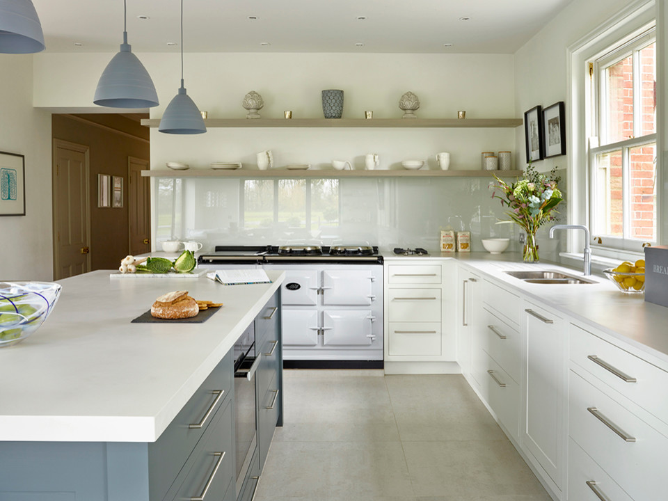 Photo of a large contemporary l-shaped eat-in kitchen in Kent with a double-bowl sink, flat-panel cabinets, white cabinets, solid surface benchtops, glass tile splashback, stainless steel appliances, ceramic floors and with island.