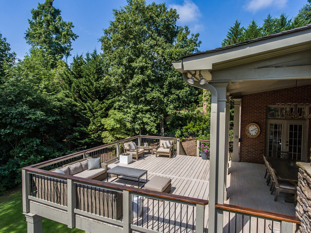 Example of a large transitional backyard deck design in Atlanta with a roof extension