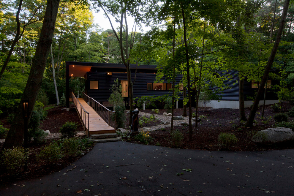 На фото: одноэтажный, черный частный загородный дом среднего размера в стиле ретро с облицовкой из металла, плоской крышей, черной крышей и отделкой планкеном