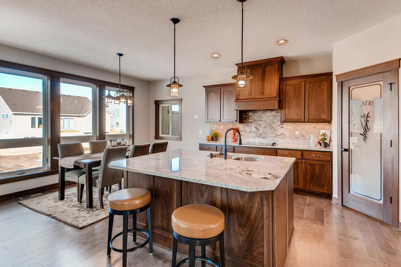 Photo of a mid-sized arts and crafts kitchen in Minneapolis with carpet, grey floor, dark wood cabinets, granite benchtops, white splashback, ceramic splashback, stainless steel appliances, with island and white benchtop.