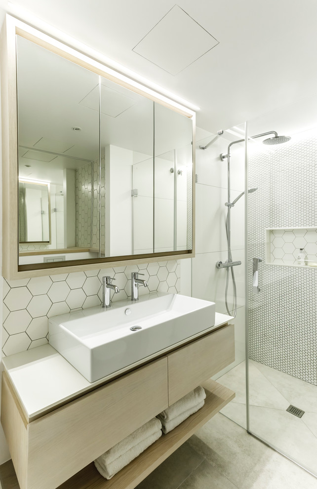 Contemporary master bathroom in Other with flat-panel cabinets, light wood cabinets, a curbless shower, white tile, white walls, a vessel sink, grey floor, a hinged shower door and white benchtops.