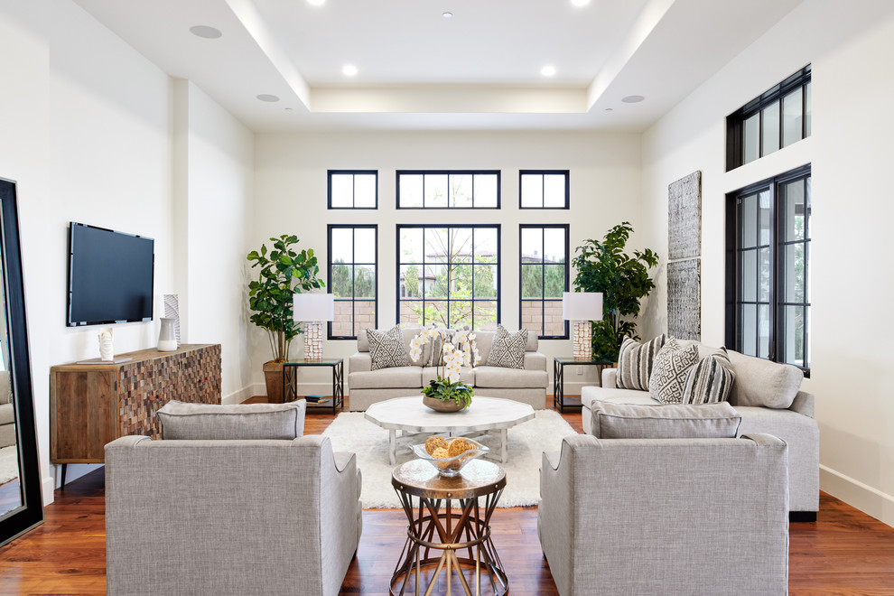 Photo of a mid-sized mediterranean open concept living room in Orange County with white walls, medium hardwood floors, a wall-mounted tv and brown floor.