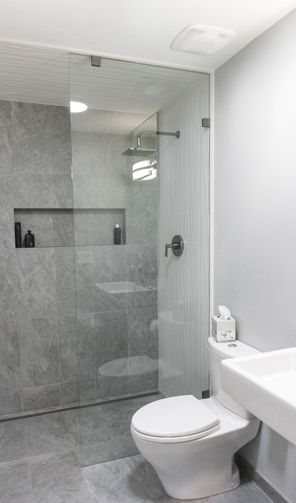 Foto på ett litet funkis badrum, med en öppen dusch, en toalettstol med separat cisternkåpa, grå kakel, travertinkakel, grå väggar, travertin golv, ett väggmonterat handfat och grått golv