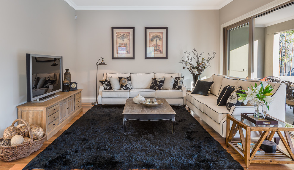 Photo of a mid-sized traditional open concept living room in Melbourne with beige walls, medium hardwood floors, a freestanding tv and brown floor.