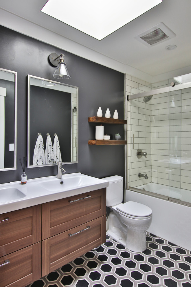 Large transitional bathroom in San Francisco with shaker cabinets, dark wood cabinets, an alcove tub, a shower/bathtub combo, white tile, black walls, an integrated sink, multi-coloured floor, white benchtops, a two-piece toilet, subway tile, cement tiles, solid surface benchtops, a sliding shower screen, a double vanity and a floating vanity.