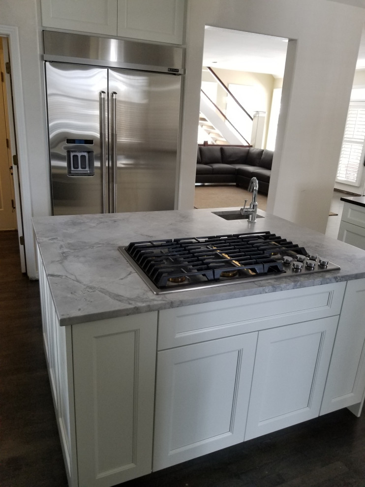 Inspiration for a large transitional u-shaped dark wood floor and brown floor eat-in kitchen remodel in Denver with an undermount sink, shaker cabinets, white cabinets, quartz countertops, stainless steel appliances, an island and black countertops