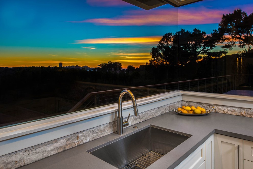 Open concept kitchen - large transitional u-shaped light wood floor open concept kitchen idea in Orange County with a single-bowl sink, shaker cabinets, white cabinets, stone tile backsplash, no island, beige backsplash, stainless steel appliances and gray countertops