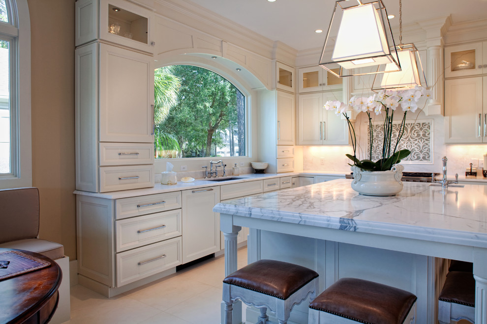 Photo of a mid-sized traditional l-shaped eat-in kitchen in Charleston with an undermount sink, recessed-panel cabinets, white cabinets, white splashback, stone tile splashback, stainless steel appliances, ceramic floors and with island.