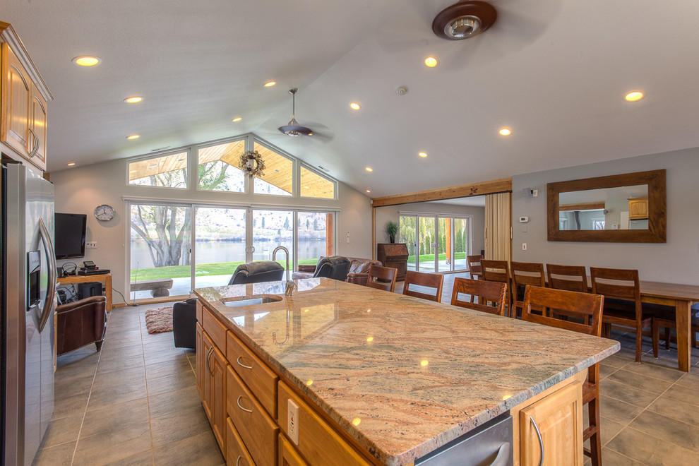 Mid-sized beach style galley eat-in kitchen in Seattle with granite benchtops, brown splashback, stainless steel appliances, ceramic floors, with island, grey floor and brown benchtop.