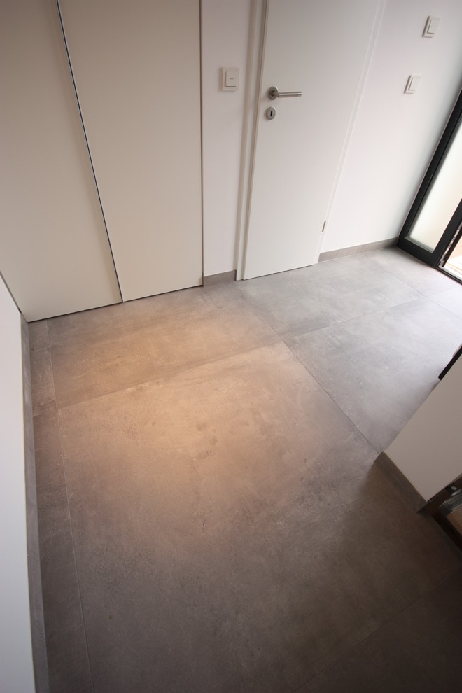 Moderner Flur mit weißer Wandfarbe und grauem Boden in Sonstige