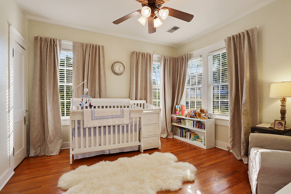 Traditional gender-neutral nursery in New Orleans with beige walls, medium hardwood floors and orange floor.