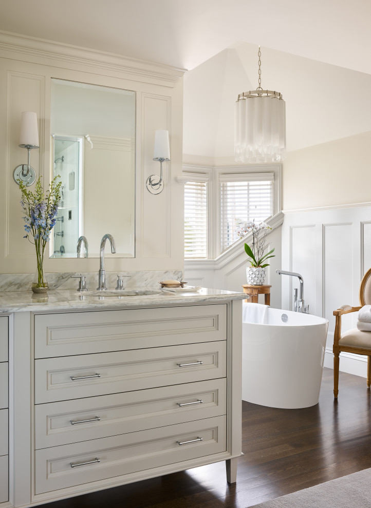 Beach style bathroom in Boston with recessed-panel cabinets, white cabinets, a freestanding tub, beige walls, dark hardwood floors, an undermount sink, brown floor, grey benchtops, a double vanity, a freestanding vanity and decorative wall panelling.