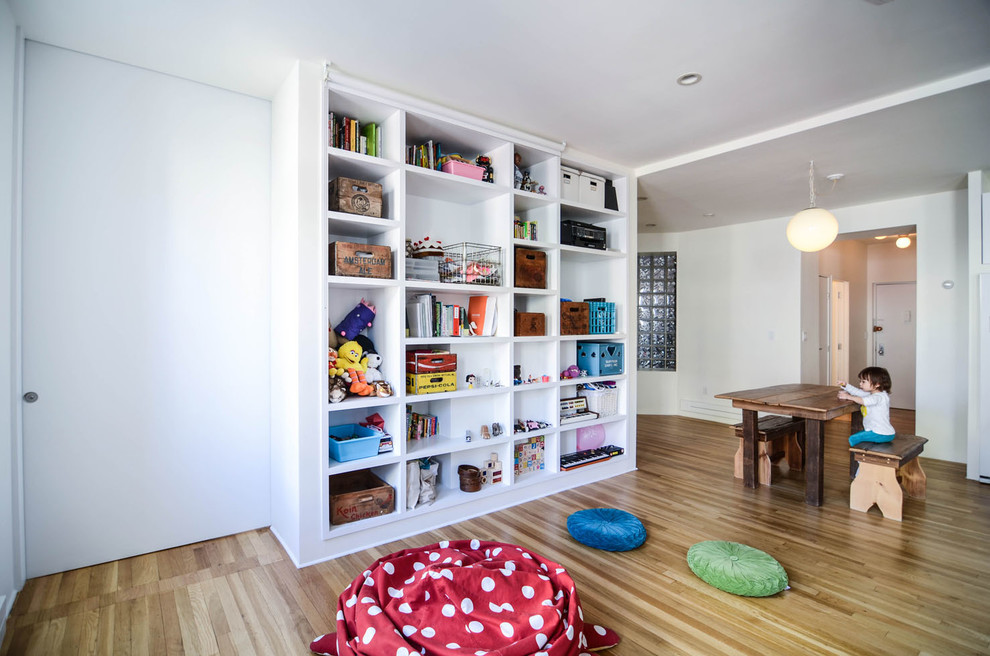 Design ideas for a modern gender-neutral kids' room in New York with white walls and light hardwood floors.