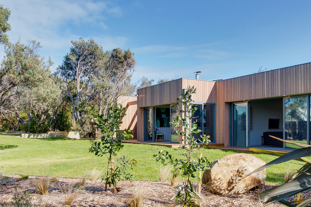 This is an example of a mid-sized contemporary one-storey house exterior in Melbourne with wood siding, a gable roof and a metal roof.