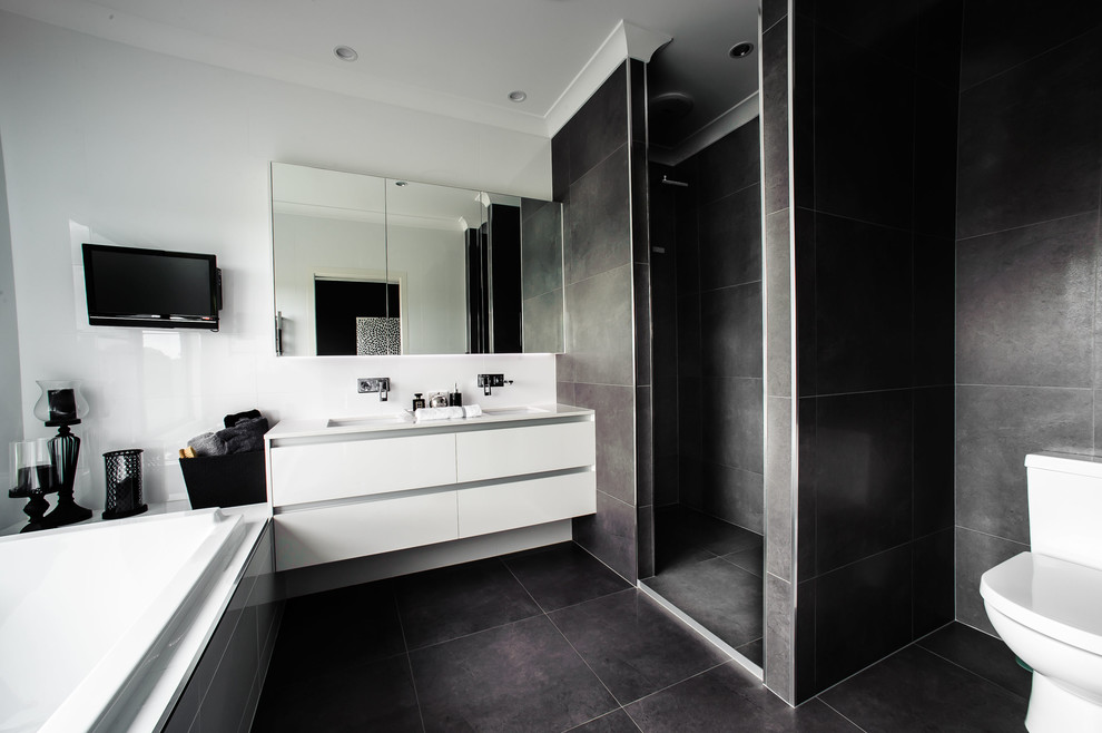 Photo of a contemporary master bathroom in Brisbane with an undermount sink, flat-panel cabinets, white cabinets, a drop-in tub, an alcove shower, a two-piece toilet, gray tile and white walls.
