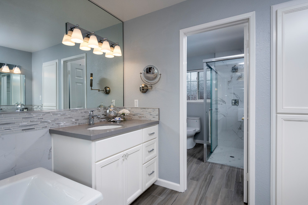 Large contemporary master bathroom in San Francisco with recessed-panel cabinets, white cabinets, a freestanding tub, a corner shower, a two-piece toilet, gray tile, porcelain tile, grey walls, porcelain floors, an undermount sink, engineered quartz benchtops, grey floor and a sliding shower screen.