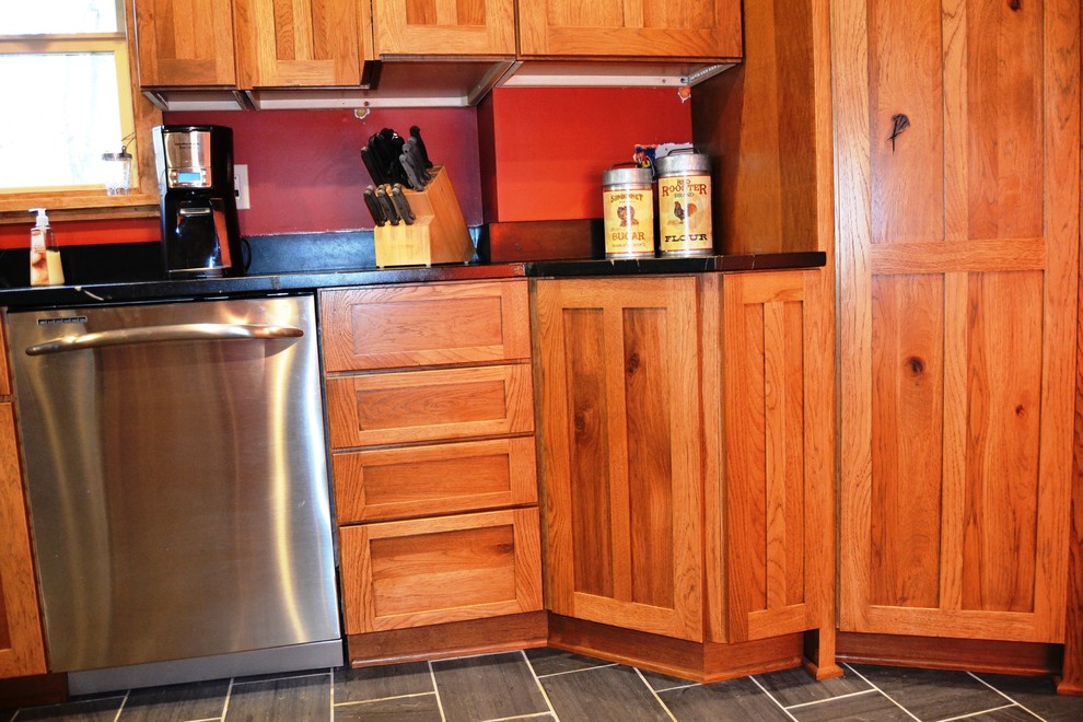 Example of a mid-sized mountain style l-shaped slate floor eat-in kitchen design in Burlington with an undermount sink, shaker cabinets, distressed cabinets, soapstone countertops, stainless steel appliances and a peninsula