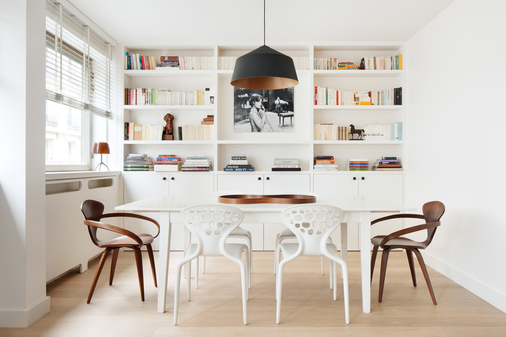 This is an example of a scandinavian dining room in Paris with white walls, light hardwood floors and no fireplace.