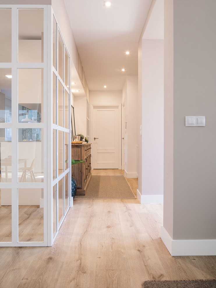 Inspiration for a mid-sized modern hallway in Bilbao with white walls, light hardwood floors and brown floor.