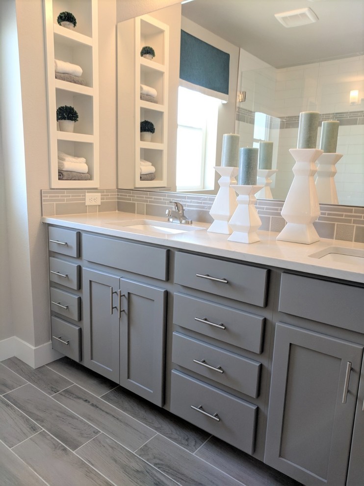 Photo of a mid-sized contemporary master bathroom in Denver with shaker cabinets, grey cabinets, a one-piece toilet, white tile, ceramic tile, grey walls, porcelain floors, an undermount sink, engineered quartz benchtops, grey floor, white benchtops, an alcove shower and a hinged shower door.