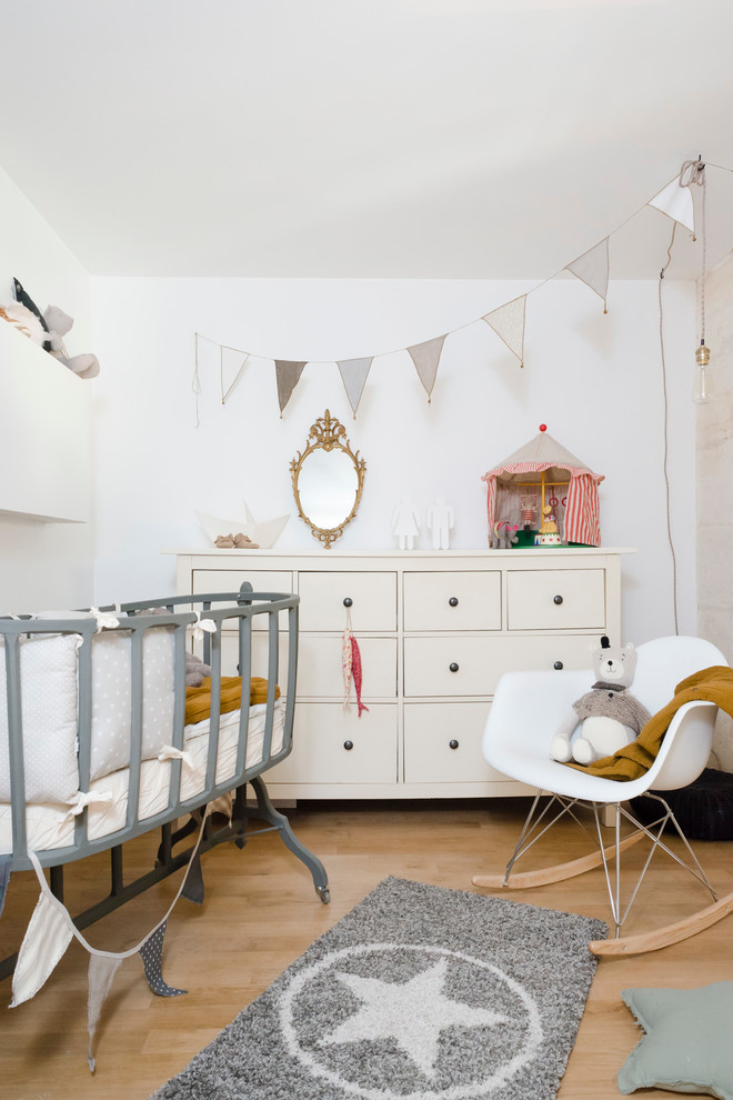 This is an example of a mid-sized scandinavian gender-neutral nursery in Bordeaux with white walls, light hardwood floors and beige floor.