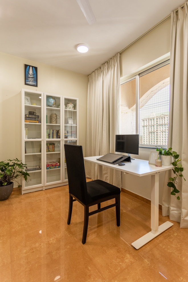 Design ideas for a mid-sized eclectic home office in Mumbai with a library, white walls, terra-cotta floors and a freestanding desk.