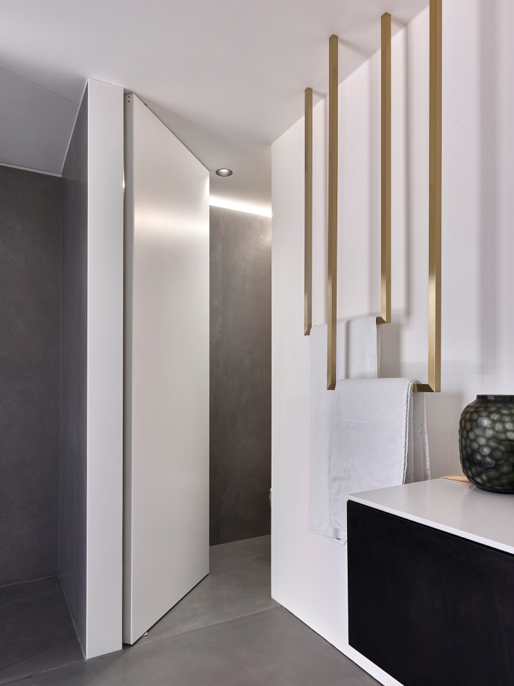 Badezimmer En Suite mit flächenbündigen Schrankfronten, weißen Schränken, bodengleicher Dusche, Wandtoilette mit Spülkasten, grauer Wandfarbe, Betonboden, integriertem Waschbecken, Beton-Waschbecken/Waschtisch, grauem Boden, offener Dusche und weißer Waschtischplatte in Munich