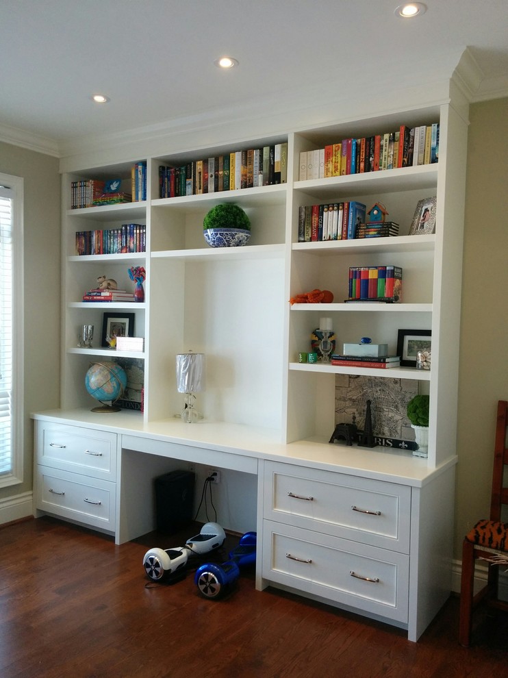 This is an example of a large transitional study room in Toronto with white walls, dark hardwood floors, no fireplace, a built-in desk and brown floor.