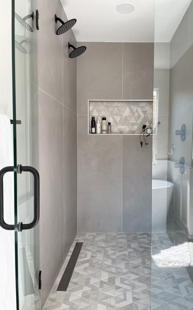 Idéer för ett mellanstort modernt vit en-suite badrum, med blå skåp, ett fristående badkar, en dubbeldusch, en toalettstol med hel cisternkåpa, grå kakel, keramikplattor, klinkergolv i keramik, ett integrerad handfat, bänkskiva i akrylsten, dusch med gångjärnsdörr, grå väggar och vitt golv