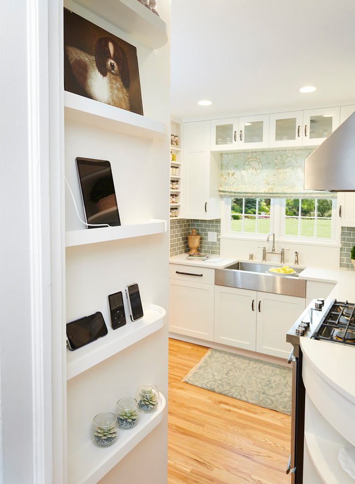 Example of a small transitional u-shaped medium tone wood floor eat-in kitchen design with a farmhouse sink, shaker cabinets, white cabinets, quartz countertops, blue backsplash, ceramic backsplash, stainless steel appliances, no island and white countertops