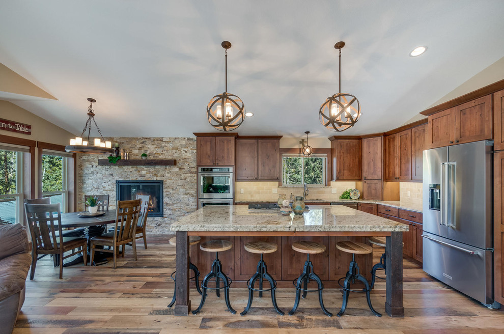 Inspiration for a large rustic l-shaped medium tone wood floor and brown floor enclosed kitchen remodel in Denver with an undermount sink, shaker cabinets, medium tone wood cabinets, granite countertops, beige backsplash, stone tile backsplash, stainless steel appliances and an island