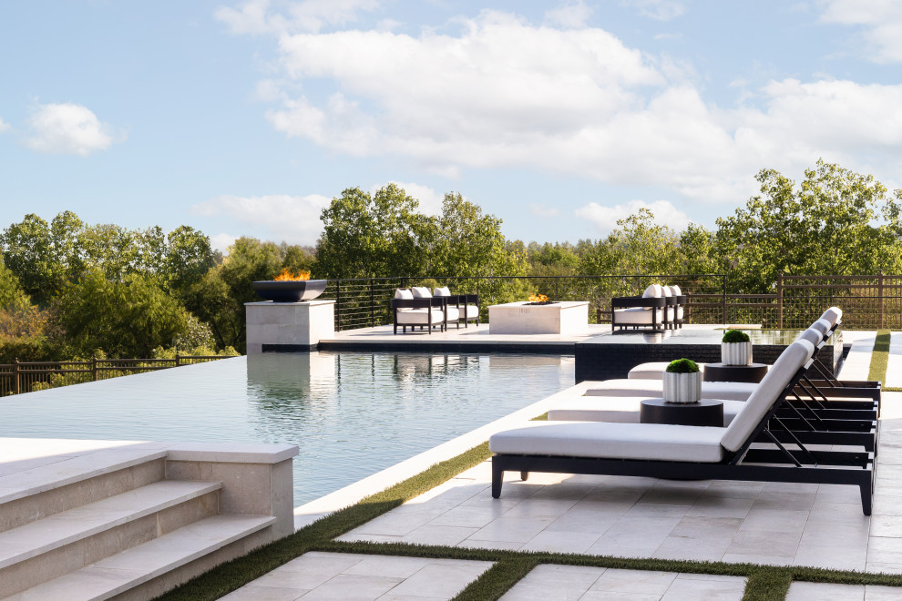 Expansive contemporary rectangular infinity swimming pool in Dallas with natural stone paving.
