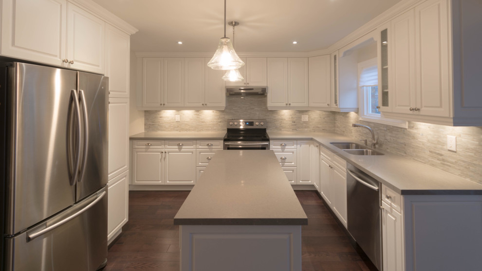 Example of a mid-sized transitional l-shaped dark wood floor and brown floor eat-in kitchen design in Toronto with a double-bowl sink, raised-panel cabinets, white cabinets, quartz countertops, gray backsplash, glass tile backsplash, stainless steel appliances, an island and gray countertops