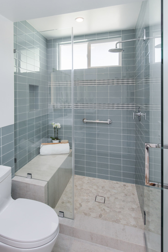 This is an example of a mid-sized beach style 3/4 bathroom in Los Angeles with flat-panel cabinets, grey cabinets, an open shower, a one-piece toilet, gray tile, ceramic tile, grey walls, ceramic floors, an undermount sink, engineered quartz benchtops, beige floor, a hinged shower door, white benchtops, a single vanity and a floating vanity.