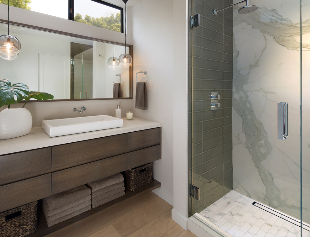 Design ideas for a mid-sized contemporary master bathroom in San Diego with flat-panel cabinets, brown cabinets, an alcove shower, a one-piece toilet, white tile, porcelain tile, beige walls, light hardwood floors, a drop-in sink, quartzite benchtops, brown floor, a hinged shower door and white benchtops.