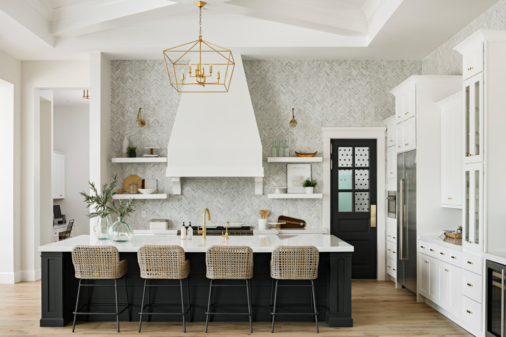 Inspiration for a transitional l-shaped kitchen in Phoenix with a farmhouse sink, shaker cabinets, grey splashback, stainless steel appliances, light hardwood floors, with island, beige floor and white benchtop.