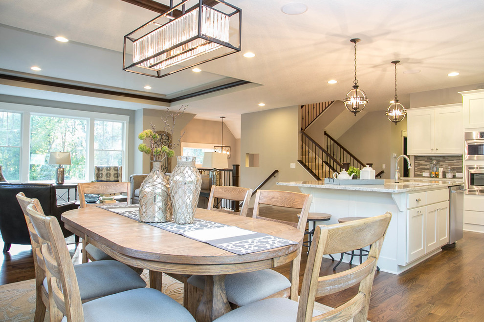 Inspiration for a transitional l-shaped medium tone wood floor eat-in kitchen remodel in Minneapolis with a drop-in sink, recessed-panel cabinets, white cabinets, granite countertops, multicolored backsplash, glass tile backsplash, stainless steel appliances and an island