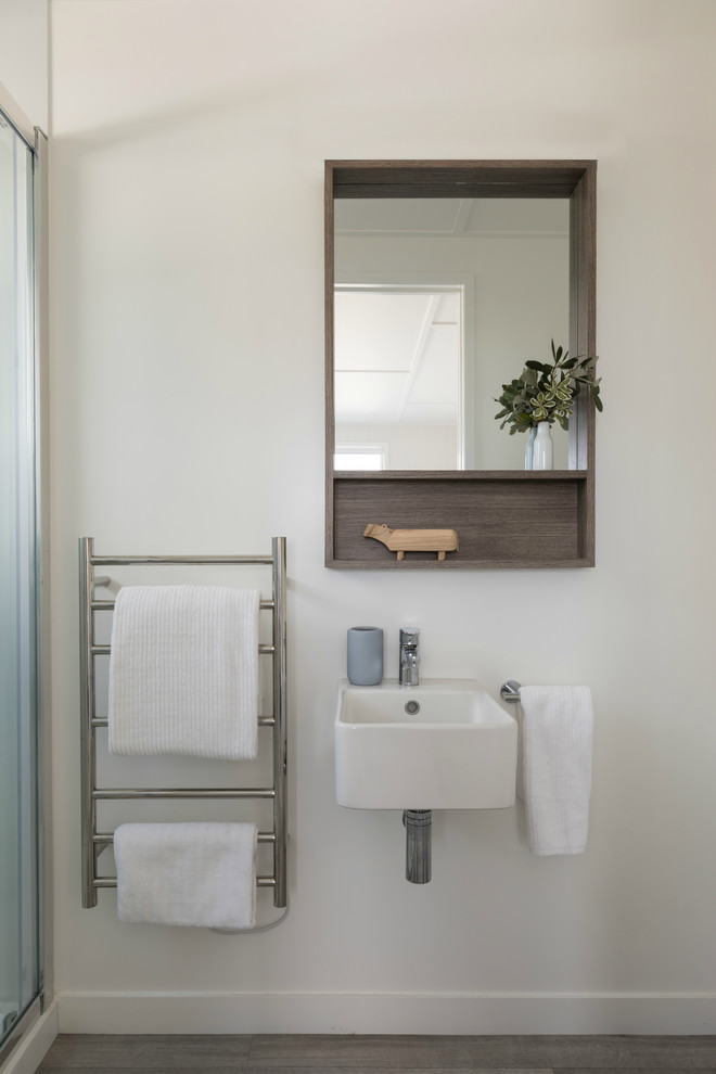 Photo of a small beach style bathroom in Auckland with an alcove shower, white walls, linoleum floors, a wall-mount sink, grey floor and a sliding shower screen.
