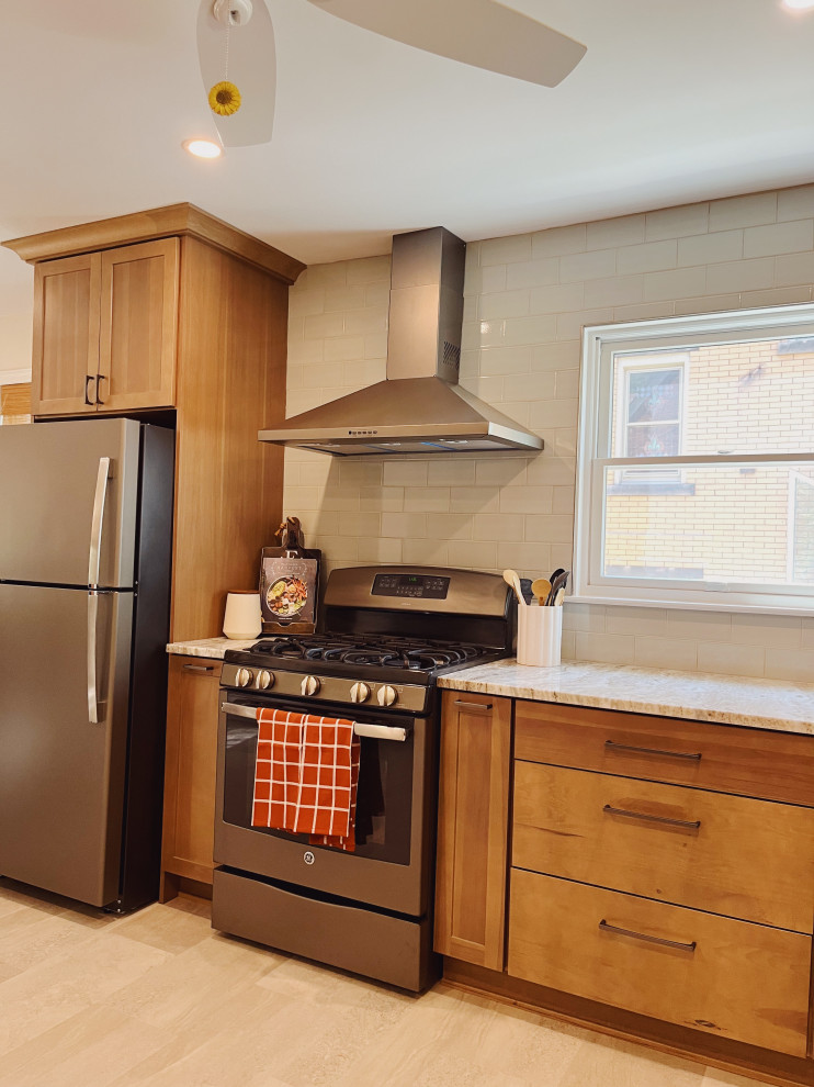 Inspiration for a mid-sized transitional l-shaped vinyl floor and beige floor eat-in kitchen remodel with a farmhouse sink, shaker cabinets, medium tone wood cabinets, quartzite countertops, green backsplash, ceramic backsplash, stainless steel appliances, no island and beige countertops
