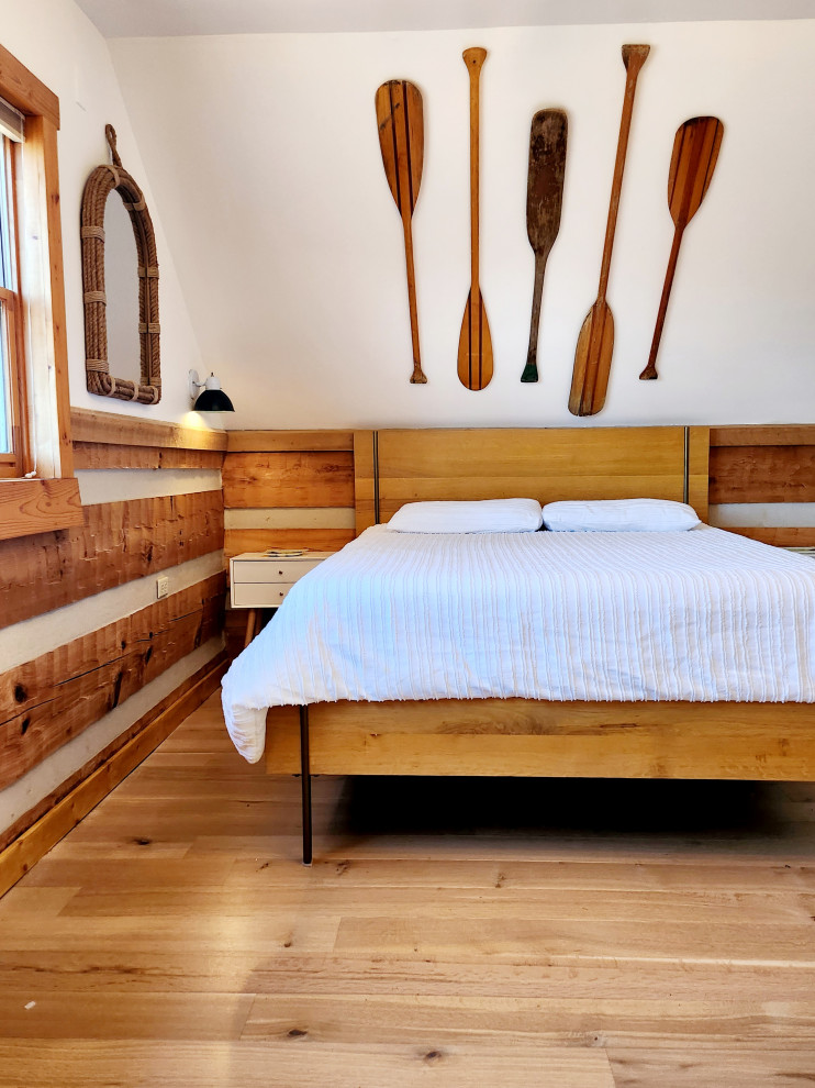 Mid-sized country loft-style bedroom in Nashville with white walls and light hardwood floors.