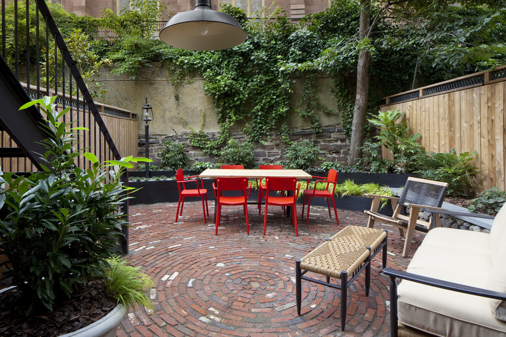This is an example of a small eclectic backyard patio in New York with brick pavers.