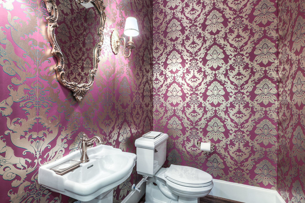This is an example of a small traditional powder room in Houston with a two-piece toilet, pink walls, dark hardwood floors and a pedestal sink.