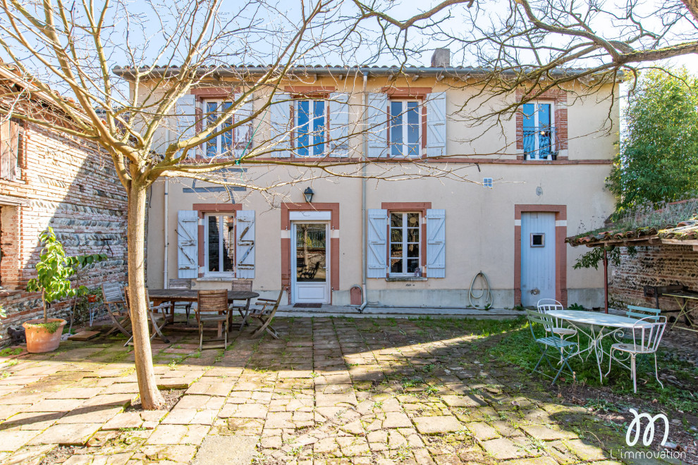Large country three-storey brick pink townhouse exterior in Toulouse with a tile roof.