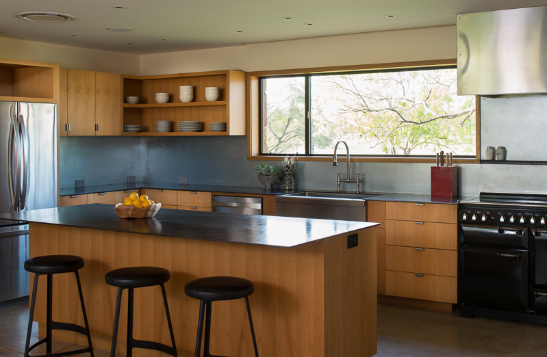 Eat-in kitchen - modern l-shaped eat-in kitchen idea in Other with a farmhouse sink, flat-panel cabinets, light wood cabinets, stainless steel countertops, metallic backsplash, metal backsplash and stainless steel appliances