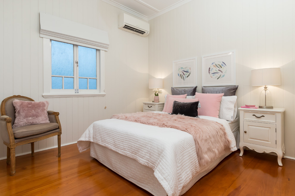 This is an example of a traditional bedroom in Brisbane with beige walls and medium hardwood floors.